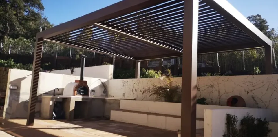 Grey frame bioclimatic pergola with a pizza oven and outdoor kitchen sink